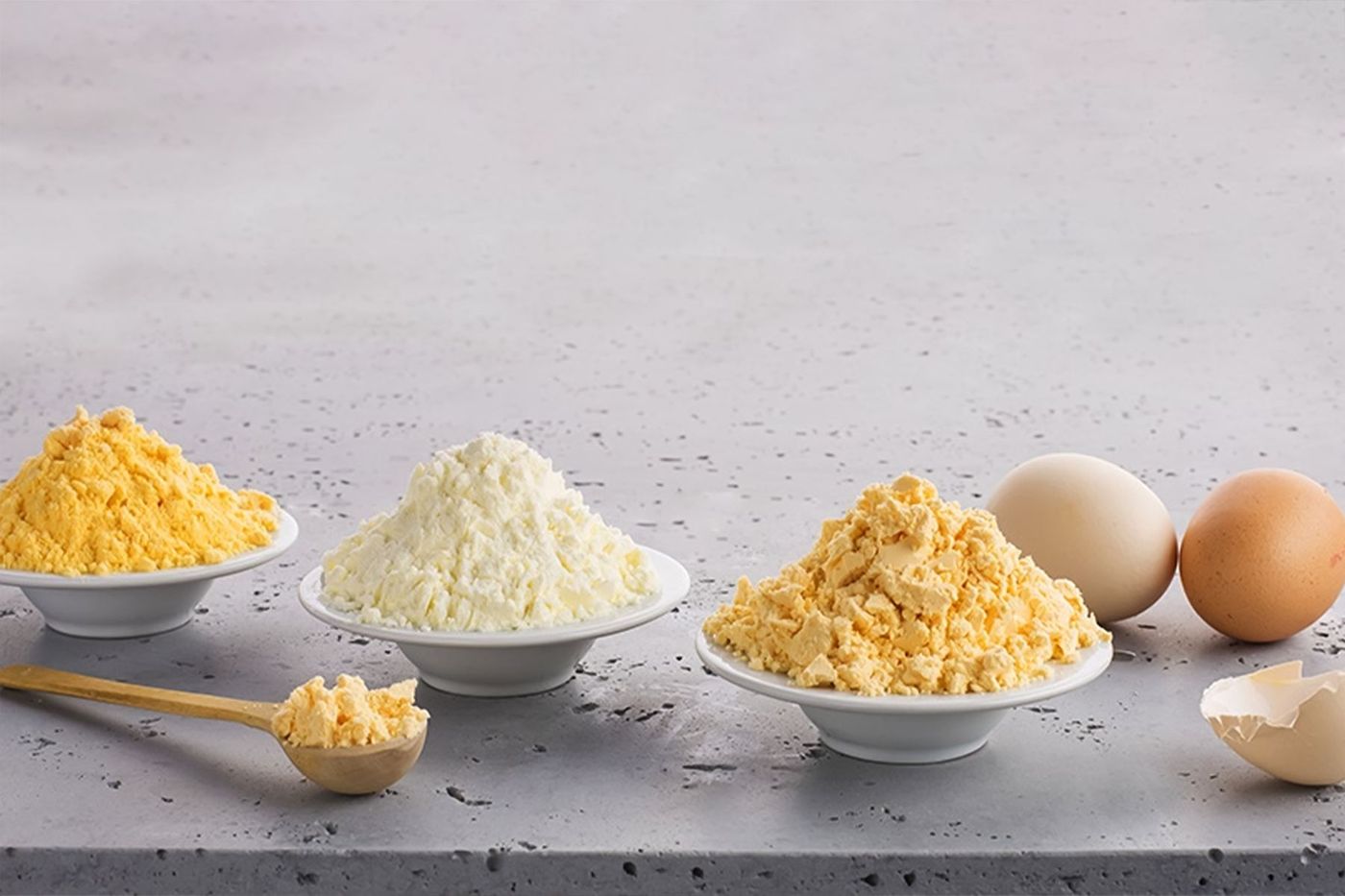 Huevo, clara y yema en polvo en tazones junto a huevos frescos